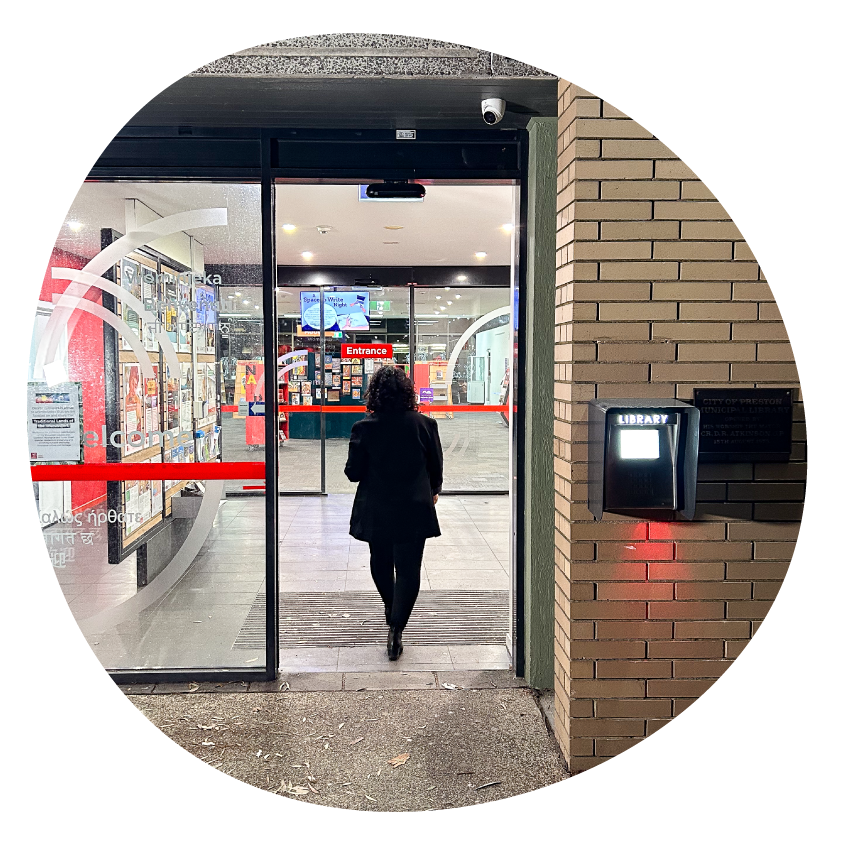 Email Image: A person walking into Preston Library at night.