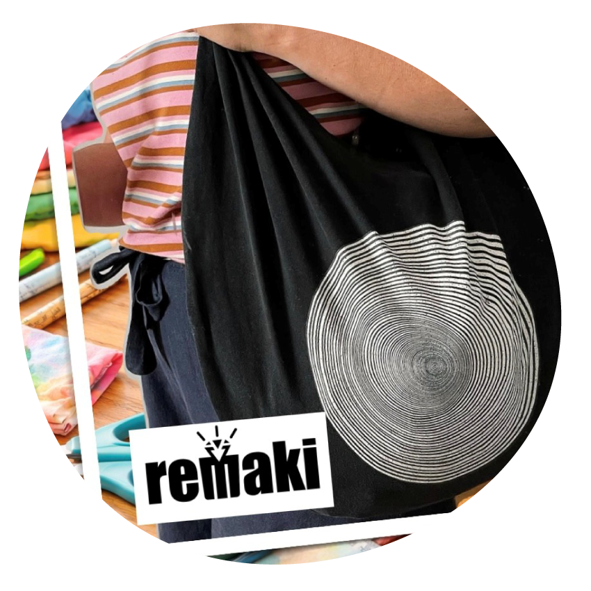 A person wearing a black recycled-T-shirt bag over one shoulder.
