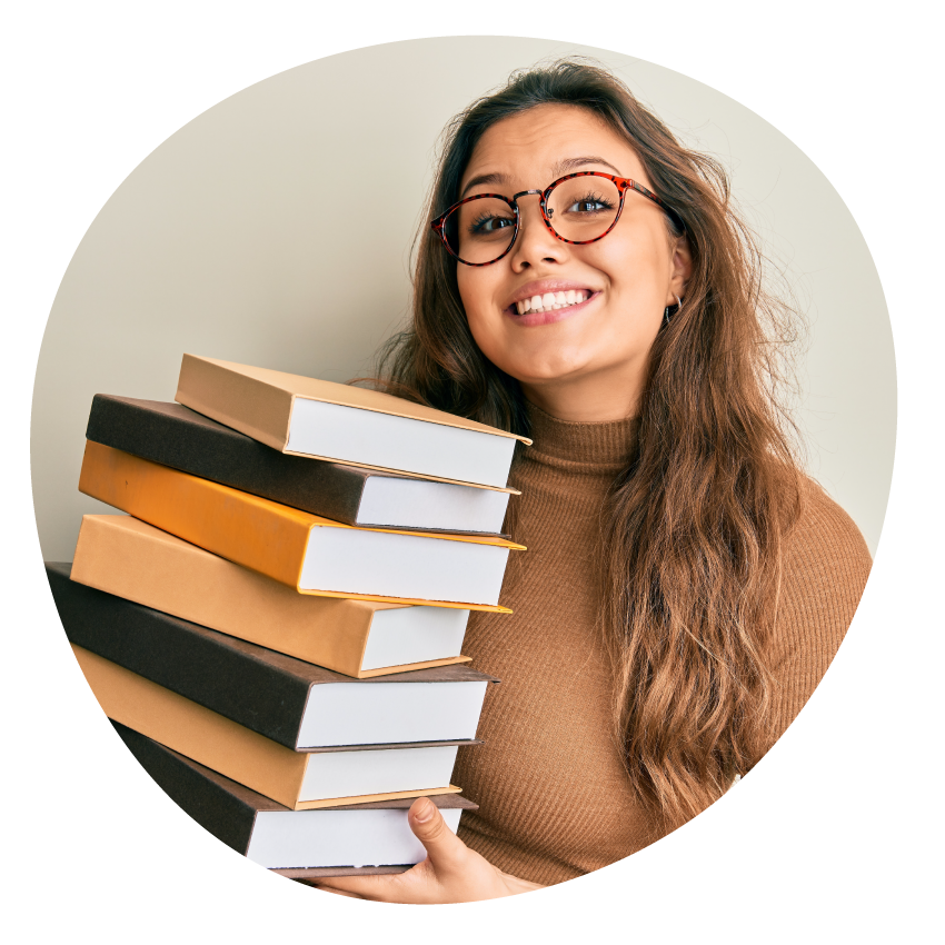 A smiling person with long hair holds a stack of books.