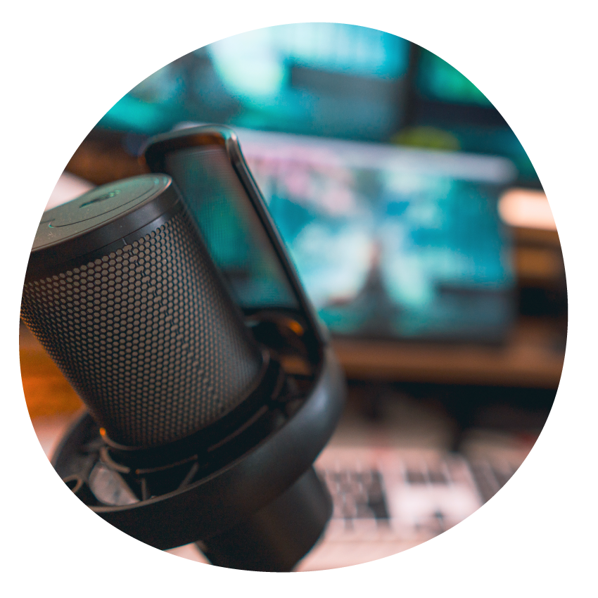 A close-up of a microphone with blurred sound equipment in the background.