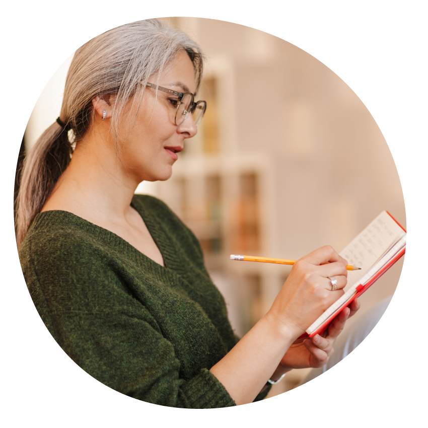 Image: A seated person in a relaxed pose writes in a notebook.