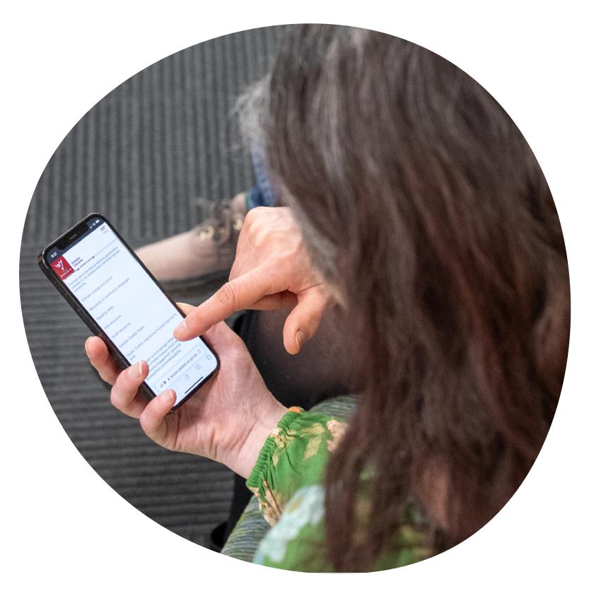 Image: Top-down view of a library staff member and customer seated together looking at a mobile phone.