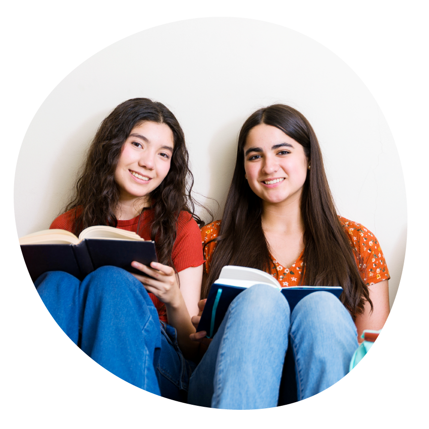 Two smiling young people sit together holding open books