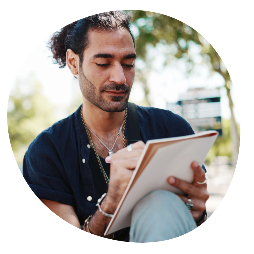 Email Image: A person sits with knee raised drawing on a notepad in an outdoor setting