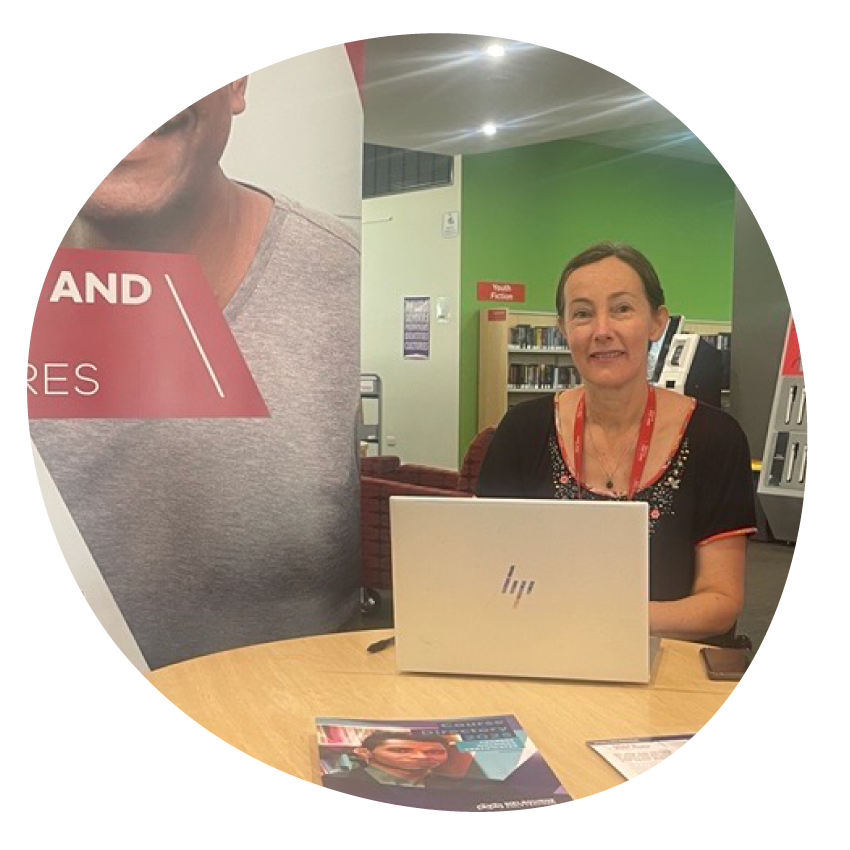 Career Counsellor smiling and seated in a library with her laptop.