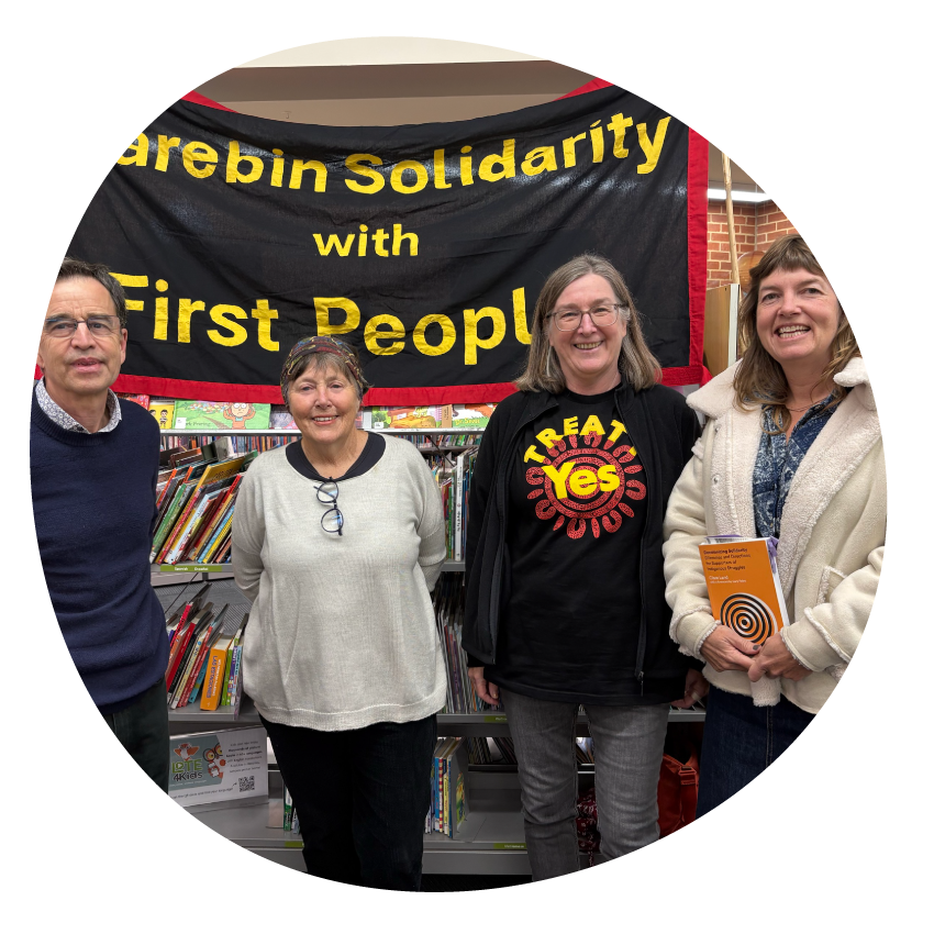 Image: A group of people stand together in front of a banner which says Darebin Solidarity with First Peoples.
