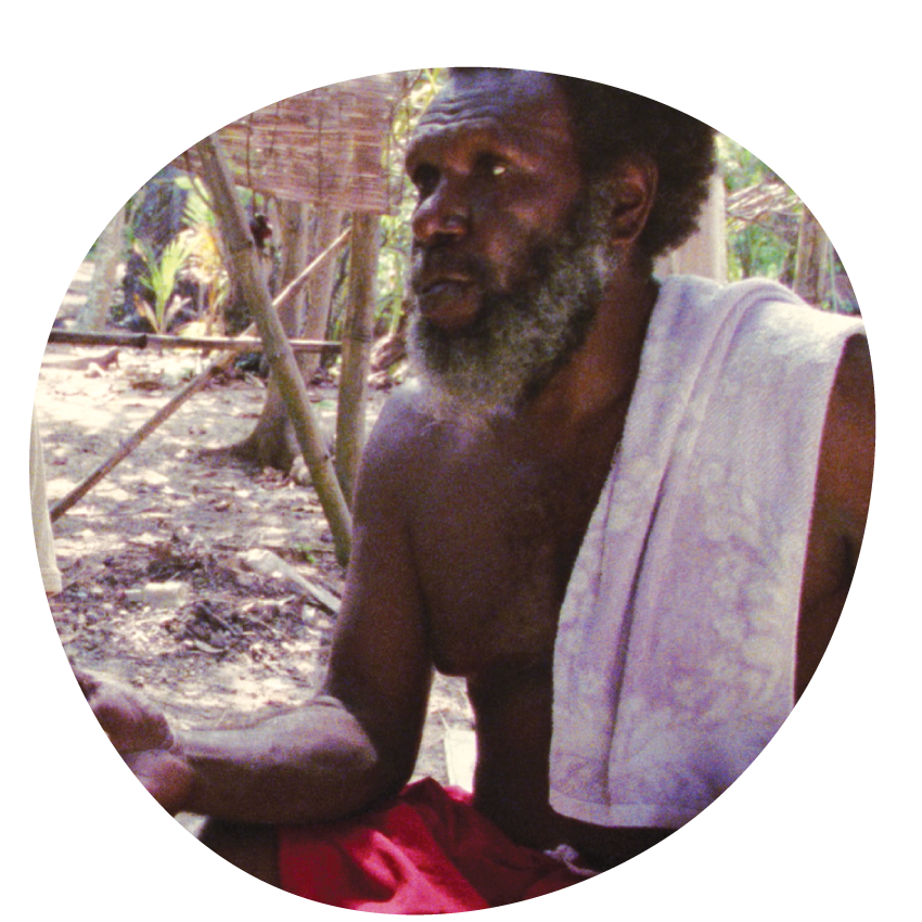 Image: Eddie Mabo sits with another man in a rural setting. Both men have white towels draped over their shoulders.