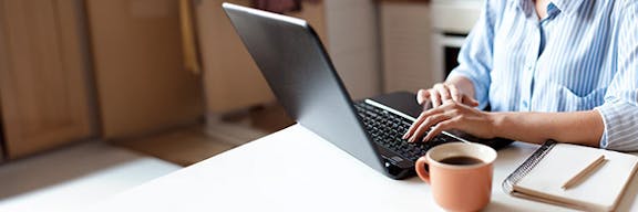 Woman sitting at desk typing on a laptop
