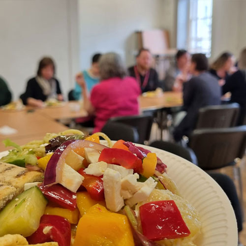 A plate of food in front of a group of people sitting
