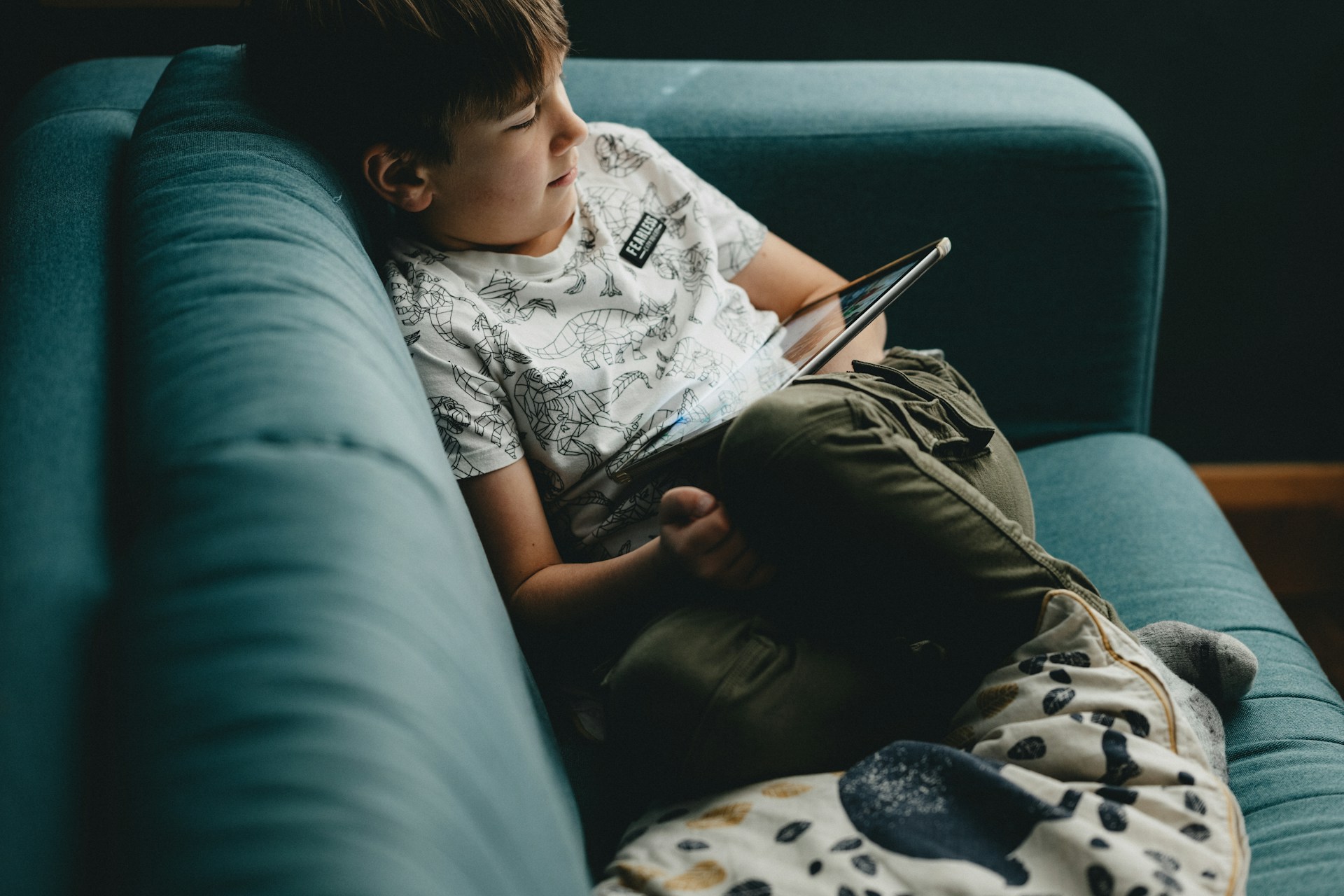 Child happily reading outside under a tree