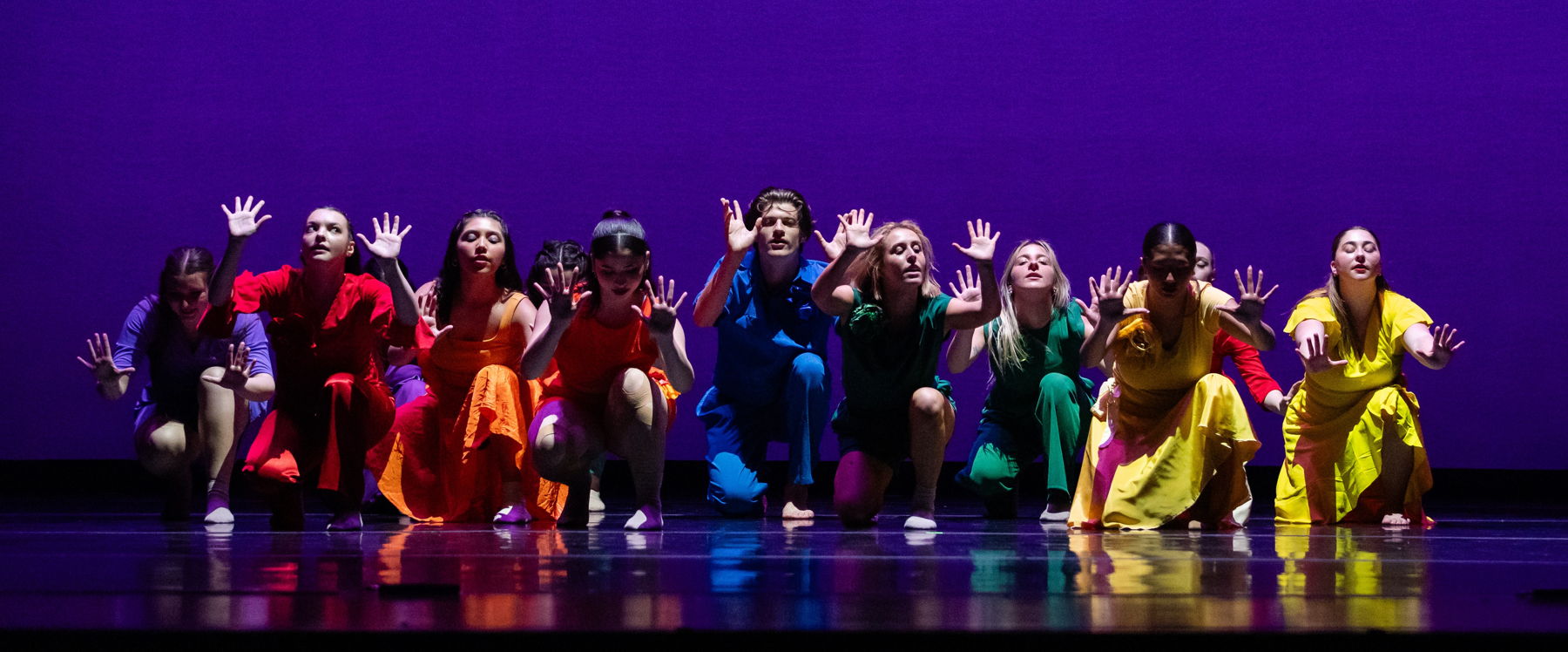 Dancers in colorful outfits performing in a jazz dance piece.