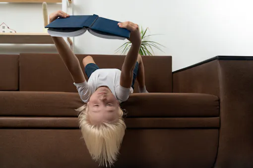 Child reading upside down hanging off a couch