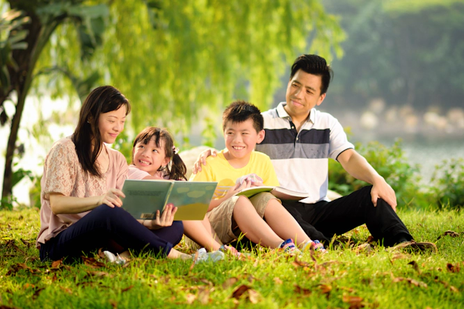Family happily reading together outdoors.