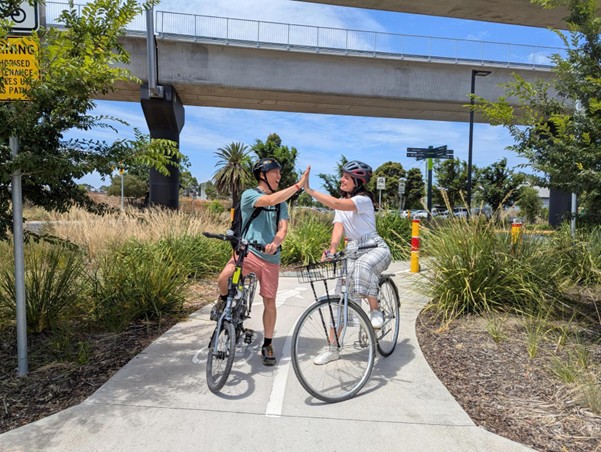Two people on bikes high fiving 