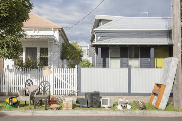 Broken items including chairs, old matresses, old and broken computers and electronics placed on a naturestrip for a hard waste collection.