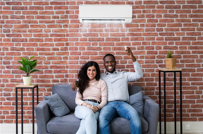 Dad and two kids all smiling, standing outside next to their hot water heat pumpEmail Image