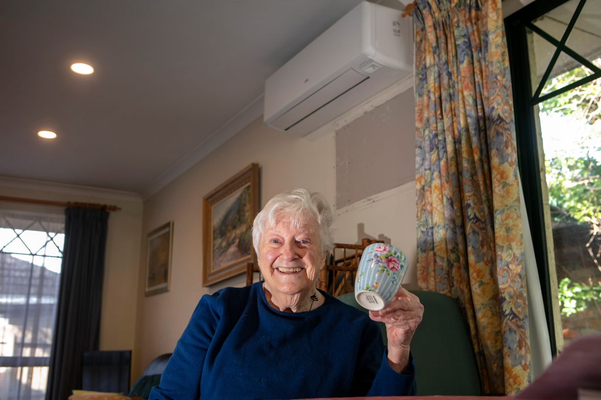 A woman holding a mug and enjoying the comfort of her reverse-cycle airconditioner