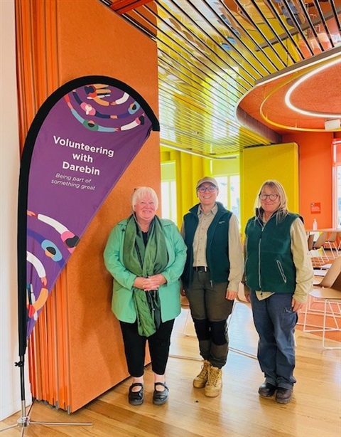 Three women standing next to a banner that says 'Volunteering with Darebin' in the Intecultural Centre in Preston.