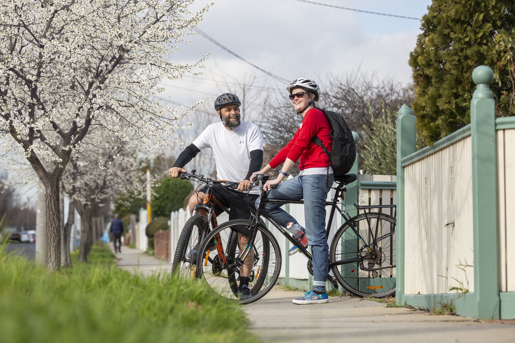Two people stand by their bikes smiling at each other in a street