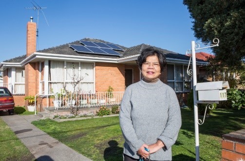 Woman standing next to home with solar panels on roof