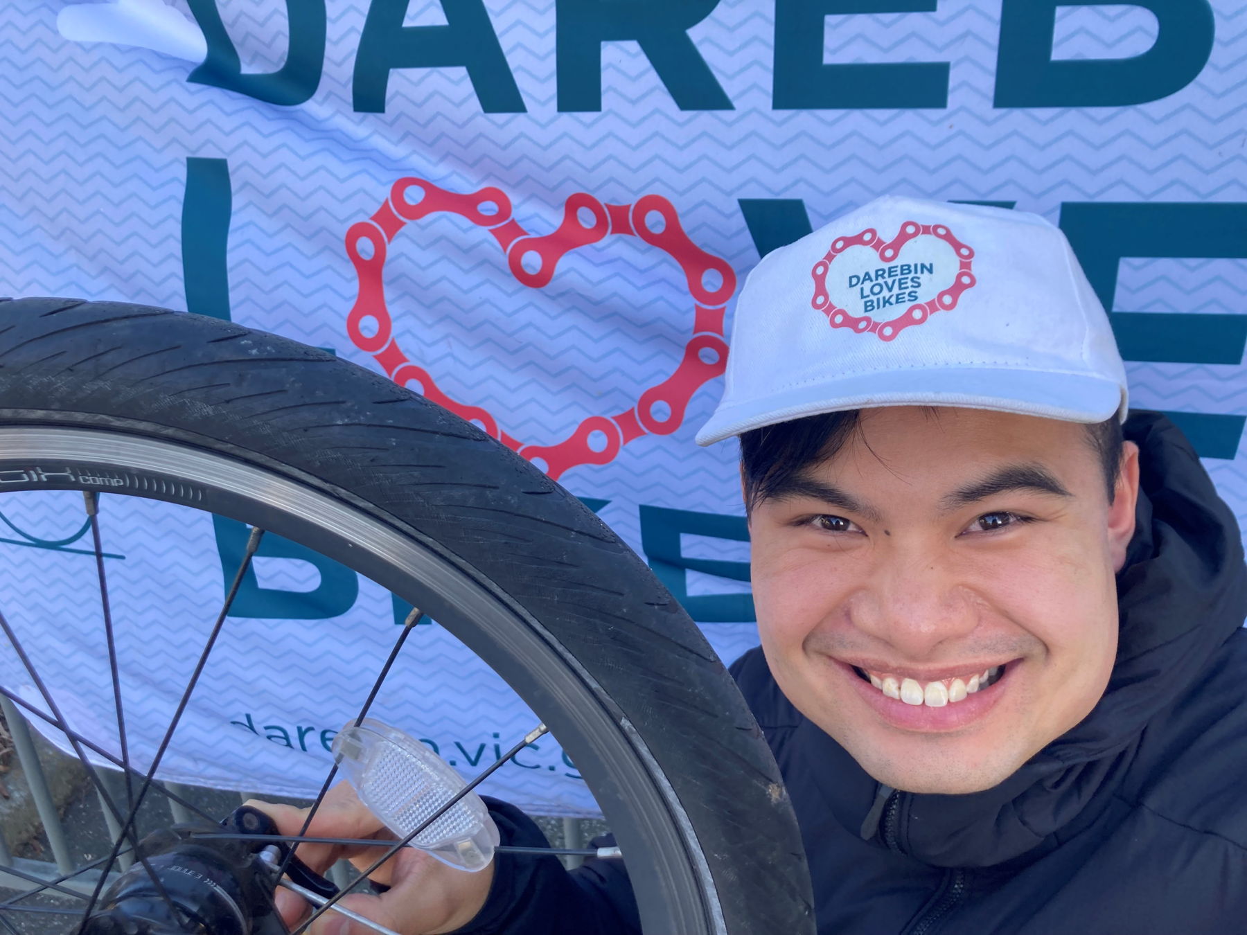 A person wearing Darebin Loves Bikes cap fixing their bike wheel