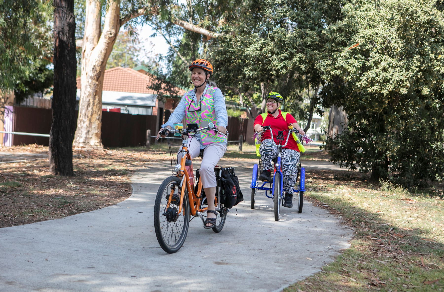 One person riding a cargo e-bike and another riding an electric trike