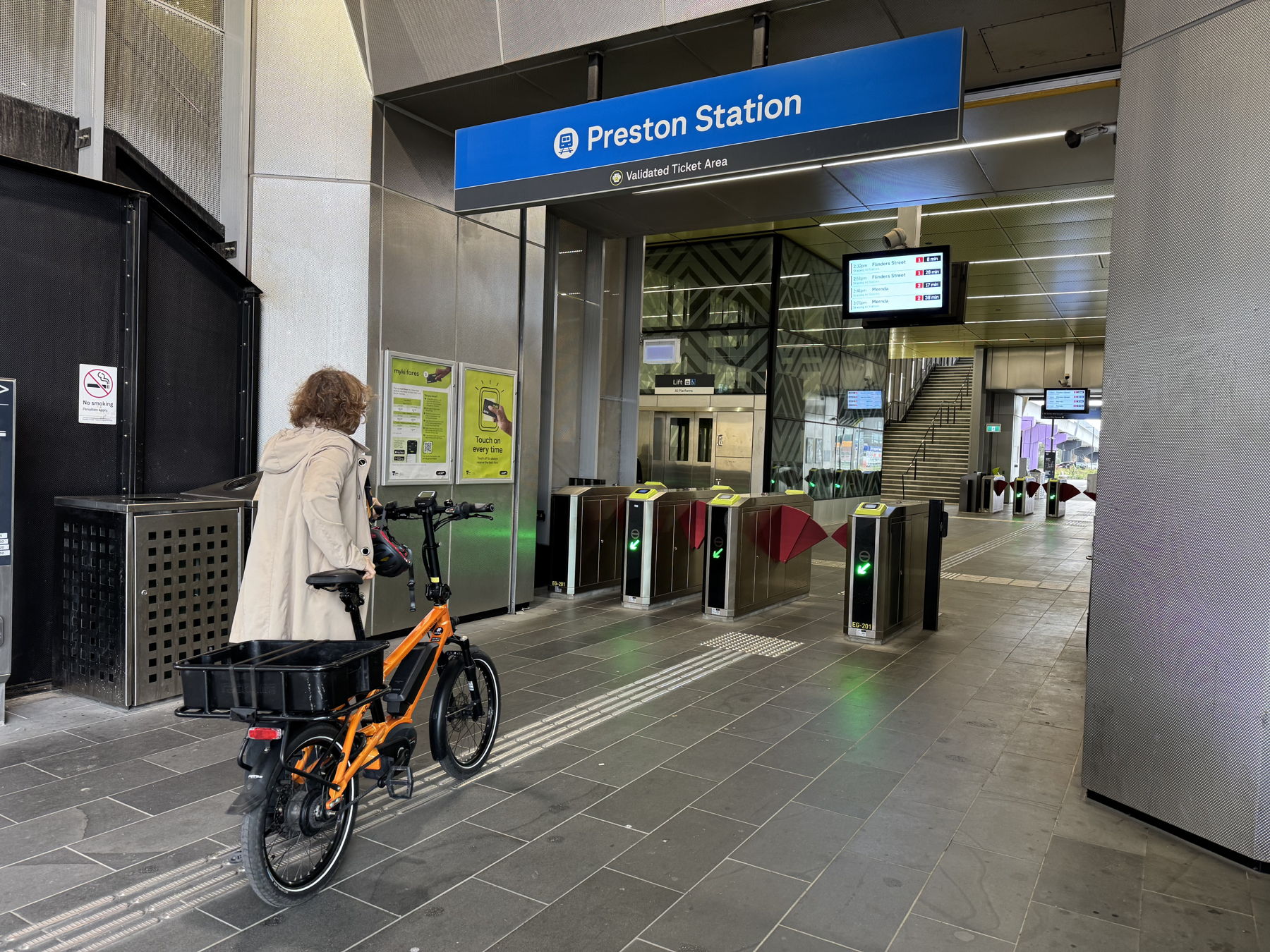 person pushing e-bike into train station