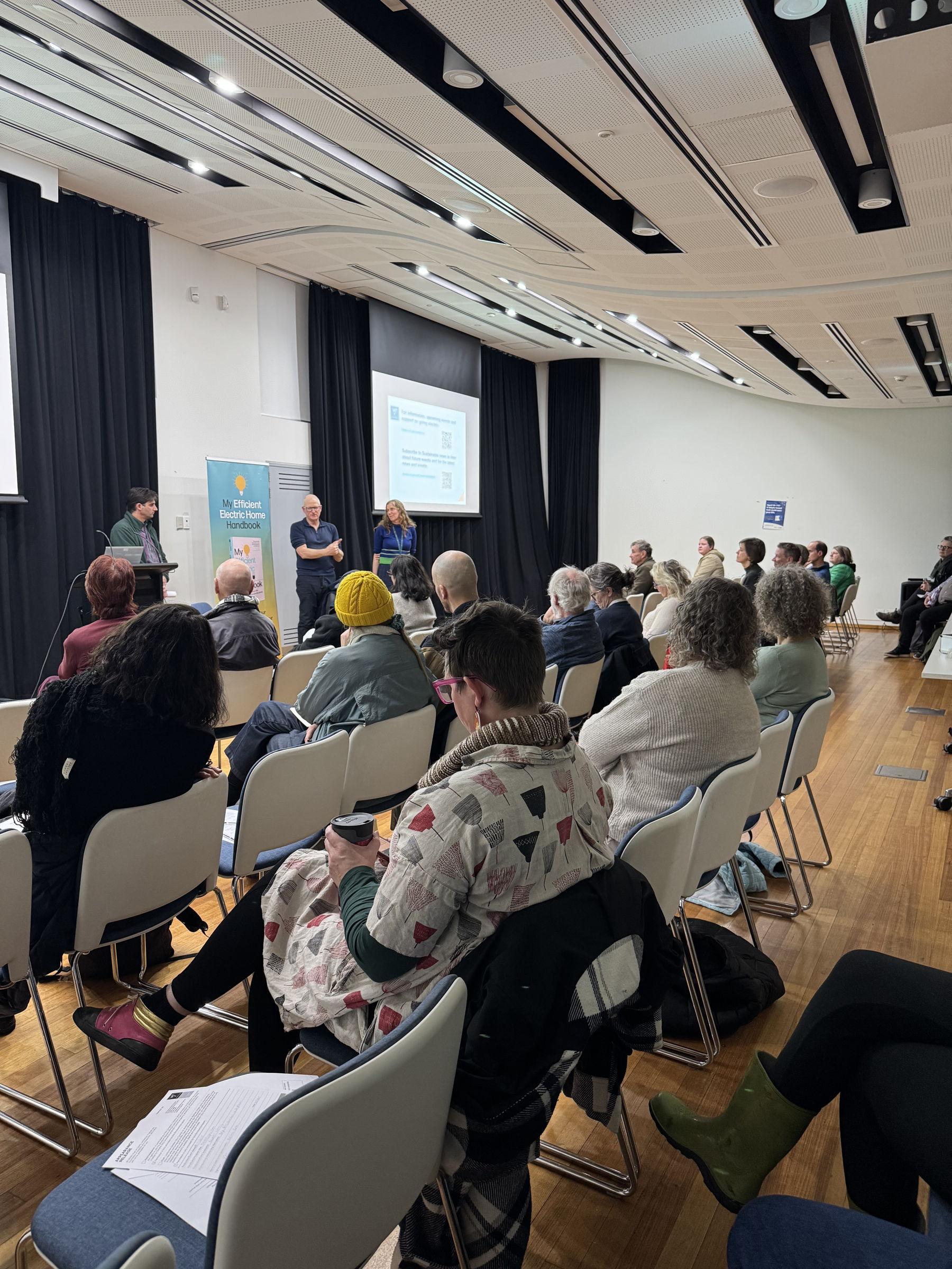 people sitting down listening to presenters in a room