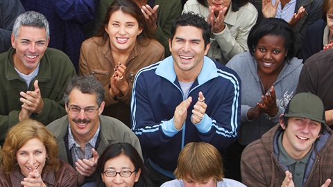 a group of people smiling, looking up towards the camera and clappingEmail Image