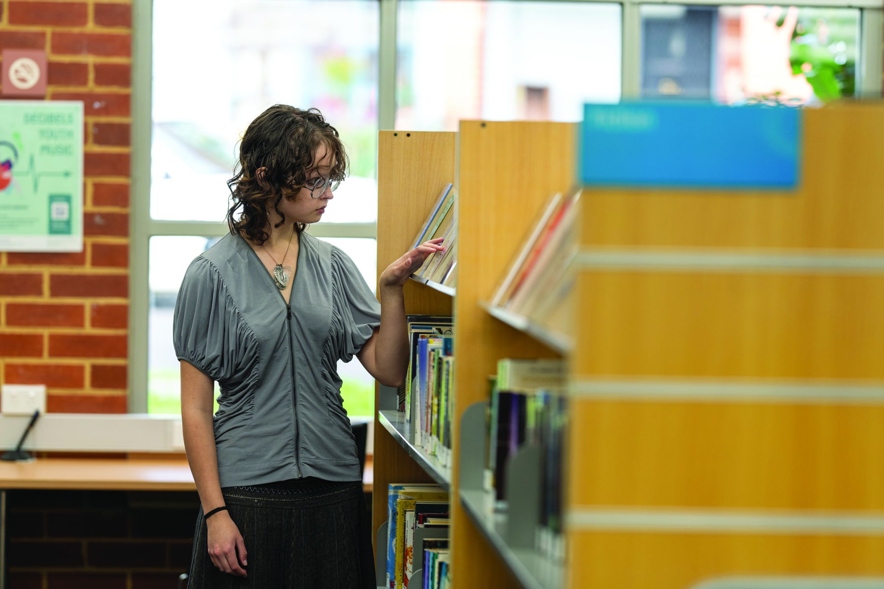 Woman looking at books on a library shelf